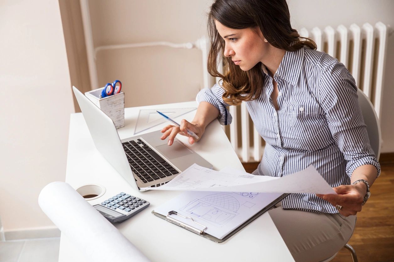 A woman sitting at her desk working on a laptop.