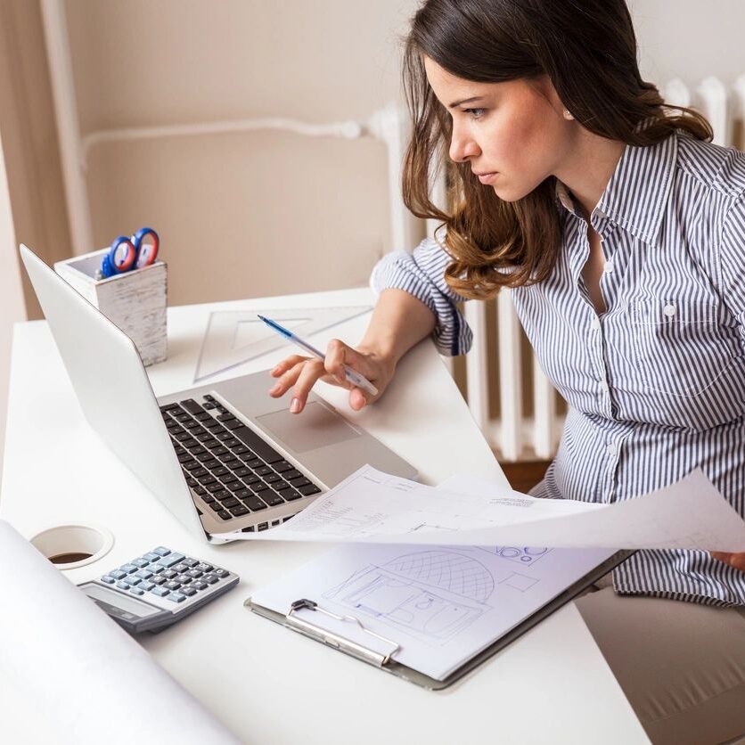 A woman sitting at her desk working on a laptop.